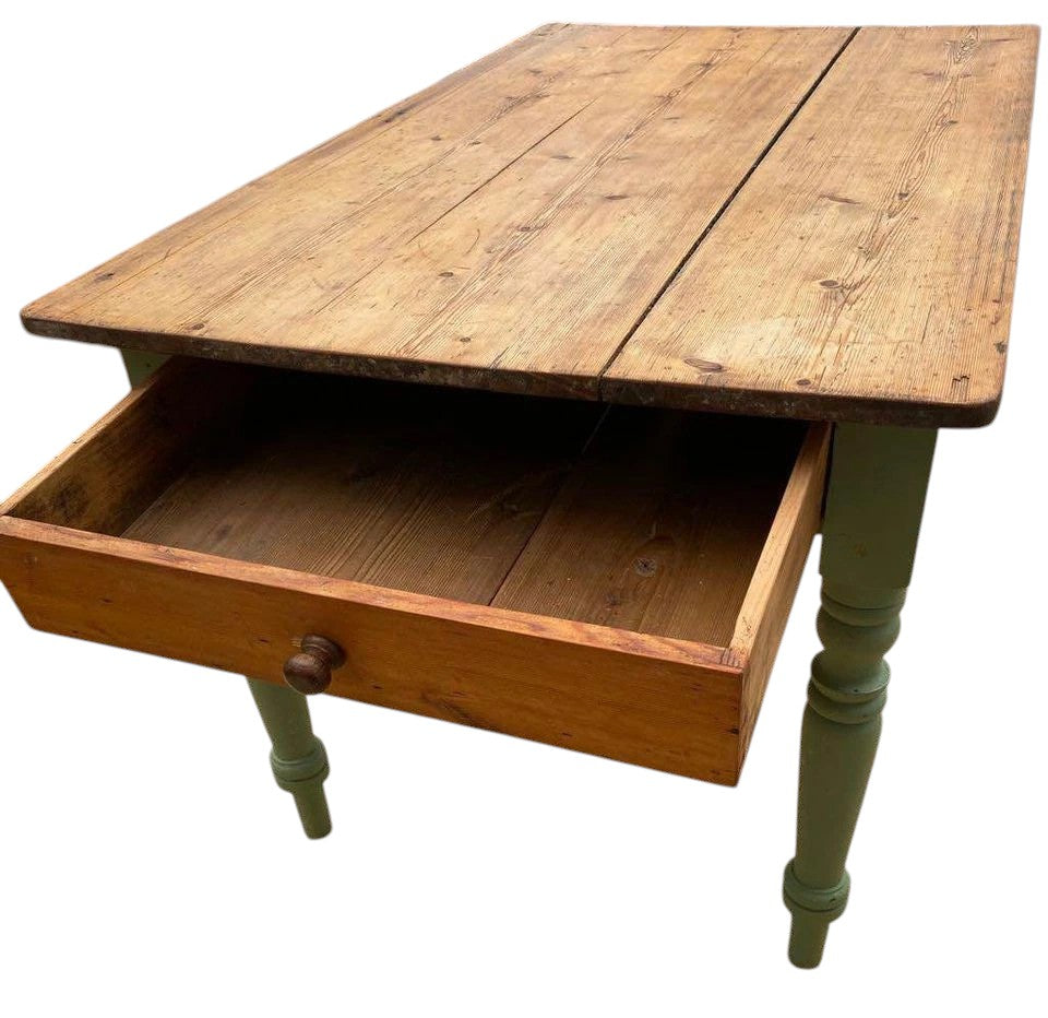 Rustic antique pine farmhouse dining table with green painted legs and open drawer.