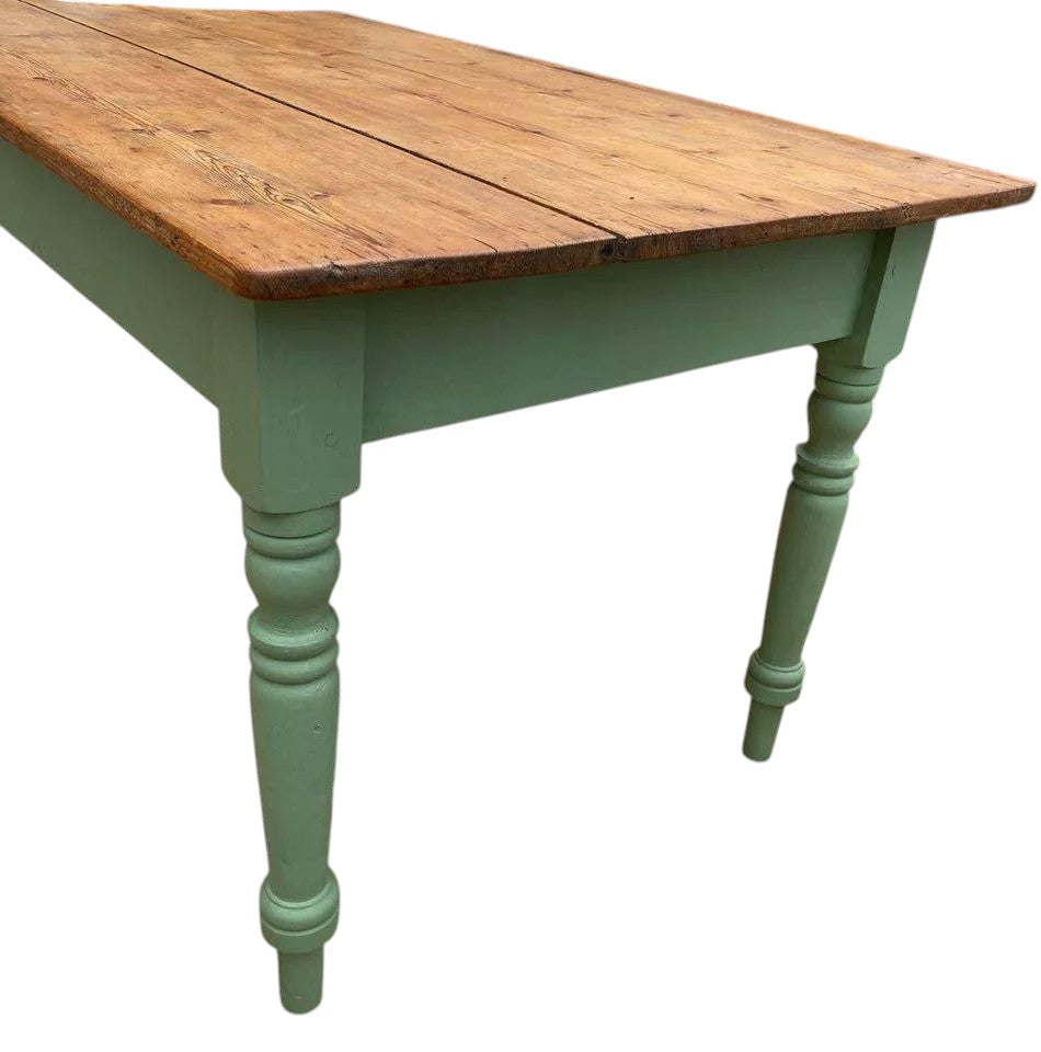 Side view of vintage farmhouse table showing turned pine legs in green paint.