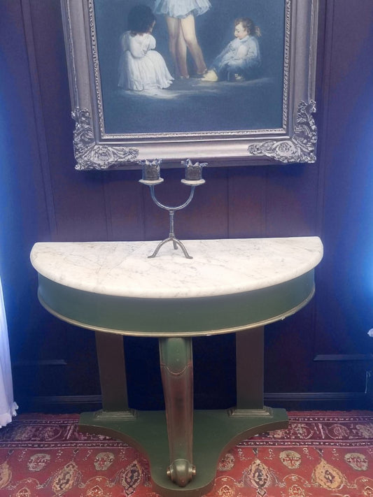 Victorian demi-lune marble top console table styled with antique décor in interior setting