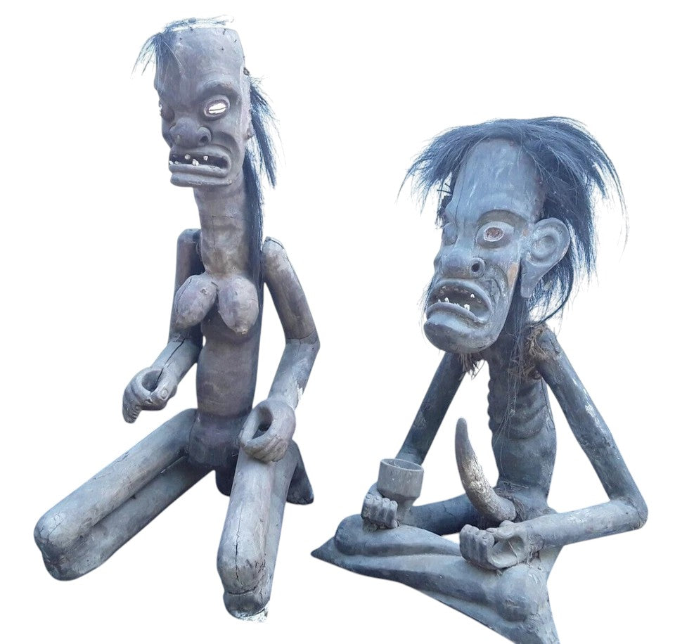 Pair of African 20th century carved wood figures with exaggerated features, shell eyes, and natural hair, male and female, in aged condition.